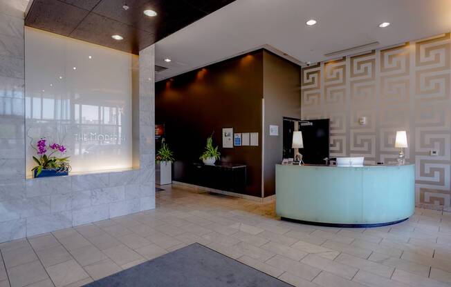 A reception area with a white counter and a black chair.