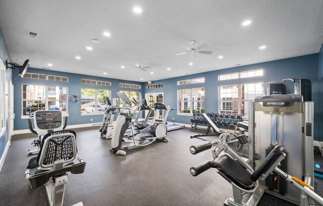 A spacious gym with a variety of equipment including treadmills, elliptical machines, and weight machines.