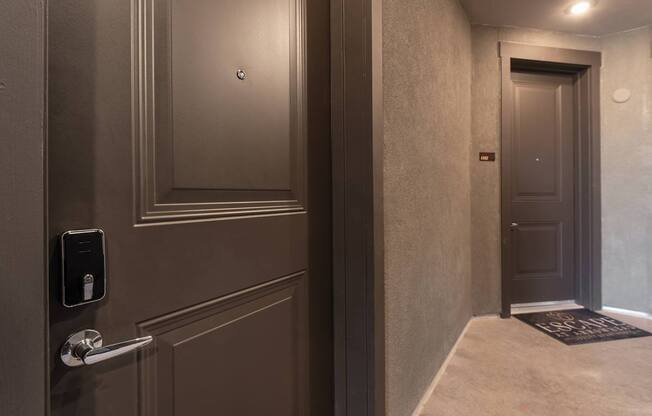 A hallway with a door and a wall-mounted device on the wall.