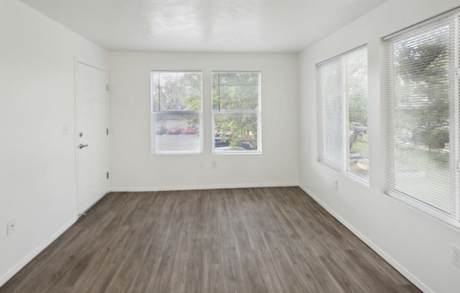 an empty living room with three windows and wood floors