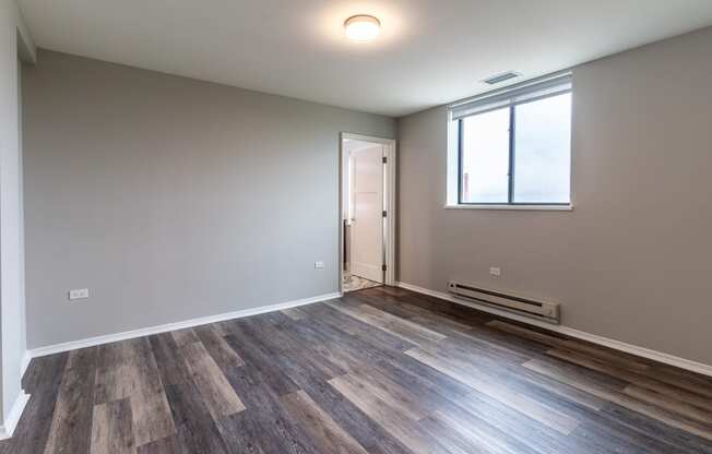 an empty living room with wood flooring and a window