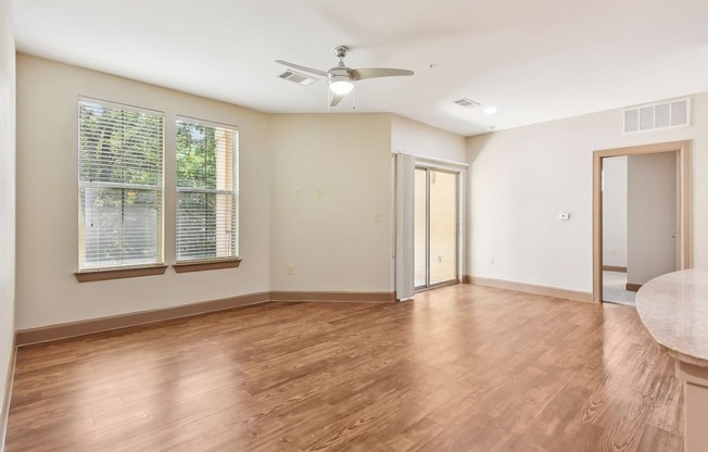 an empty living room with wood floors and a ceiling fan