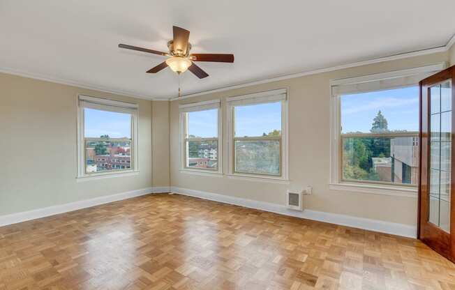 Wood Inspired Plank Flooring in Liivng Space Complete with Five Oversized Windows, A Ceiling Fan, and Views of Natural Scenery at Malloy Apartment Homes, Seattle, Washington