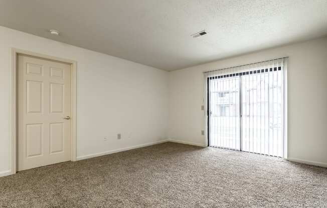 an empty living room with a door to a balcony at Pheasant Run in Lafayette, IN 47909