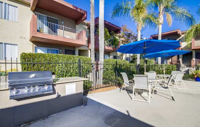 a patio with a grill and tables and umbrellas