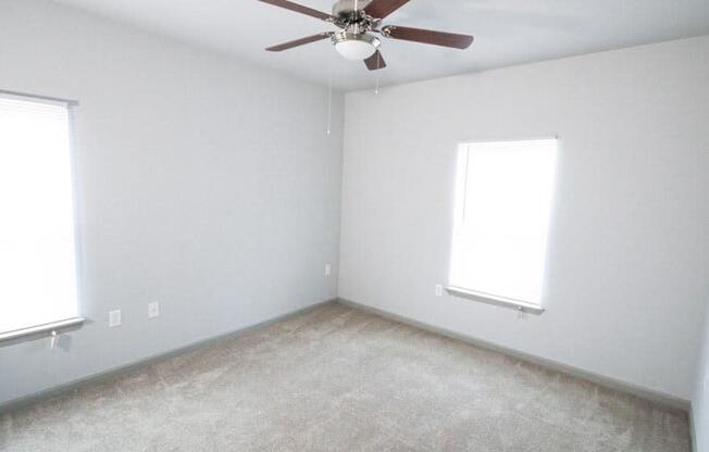 Empty bedroom with a ceiling fan and two windows at Mosaic Apartments in Avon, Indiana