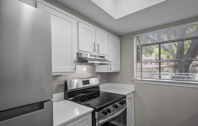 an empty kitchen with white cabinets and a window