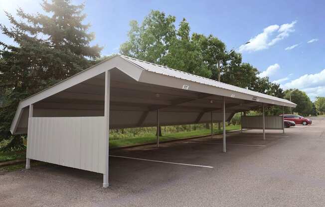 A large white carport with a metal roof is situated in a gravel parking lot.