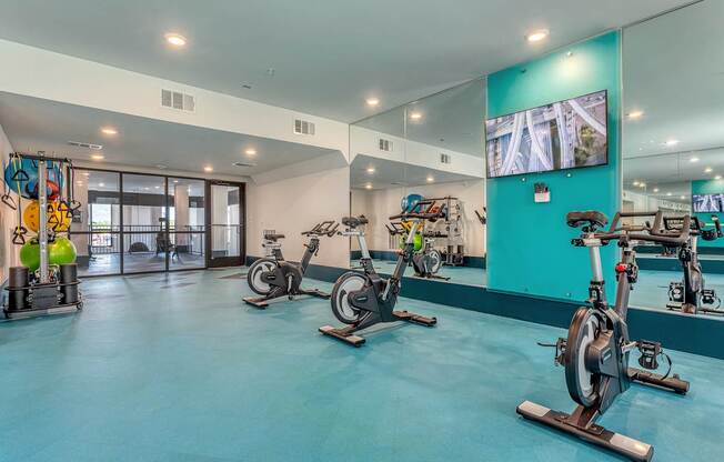 A room with exercise bikes and a television.