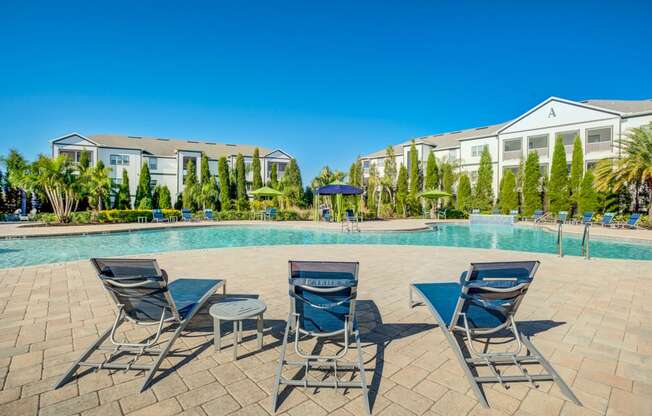 a swimming pool with chairs and tables next to a building