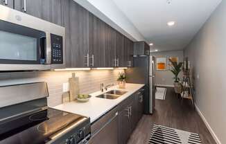 A modern kitchen with dark wood cabinets and stainless steel appliances.