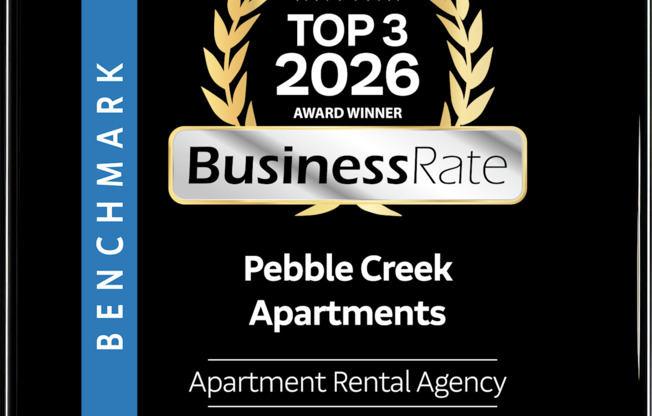 A black and gold award sign for Pebble Creek Apartments.