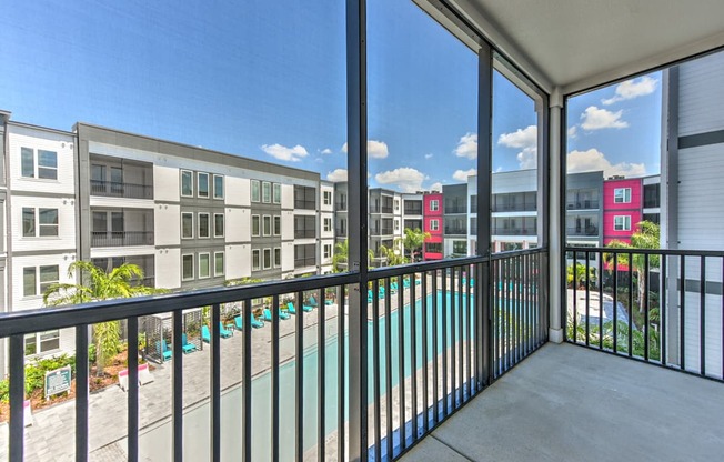 A balcony with a pool and a view of apartment buildings.