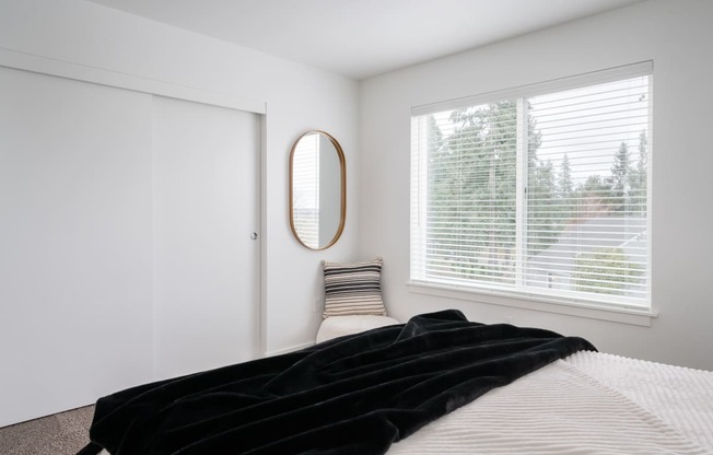 a bedroom with white walls, a large window and closet