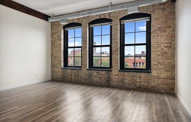 an empty room with a brick wall and three windowsat Gaar Scott Historic Lofts, Minnesota, 55401