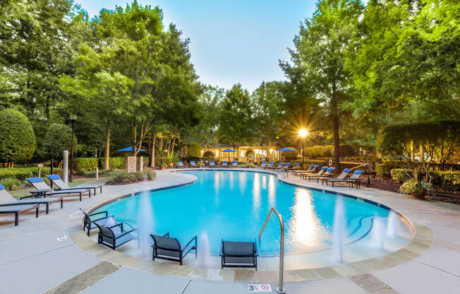 a swimming pool with chaise lounge chairs and trees in the background