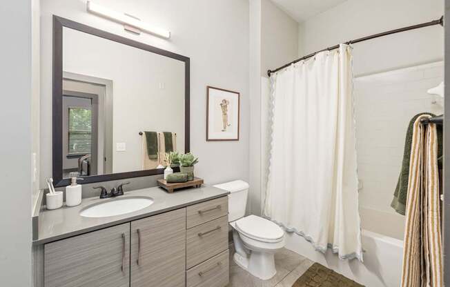 A bathroom with a toilet, sink, and shower.