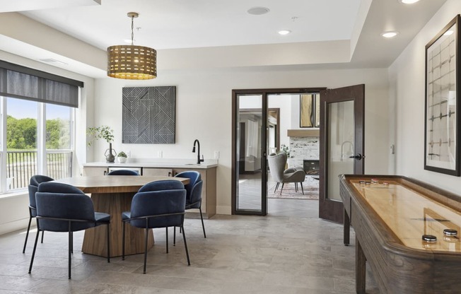 a games room with a shuffleboard table and blue chairs