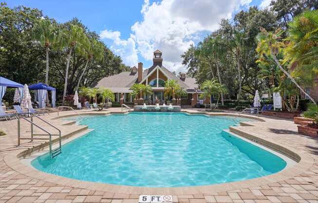 A large swimming pool surrounded by a brick patio and a gazebo in the background.