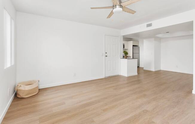 A room with a ceiling fan and light, hardwood floors, and a white door.