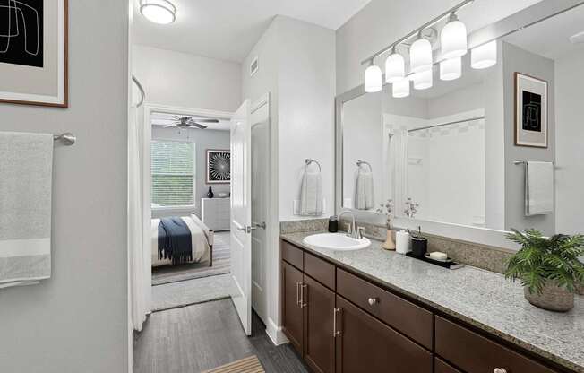 A bathroom with a white sink and brown cabinets.