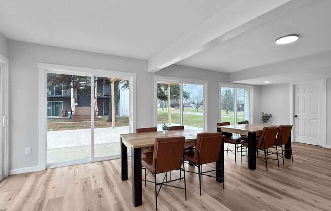 A dining room with a table and chairs and a view of a building outside.