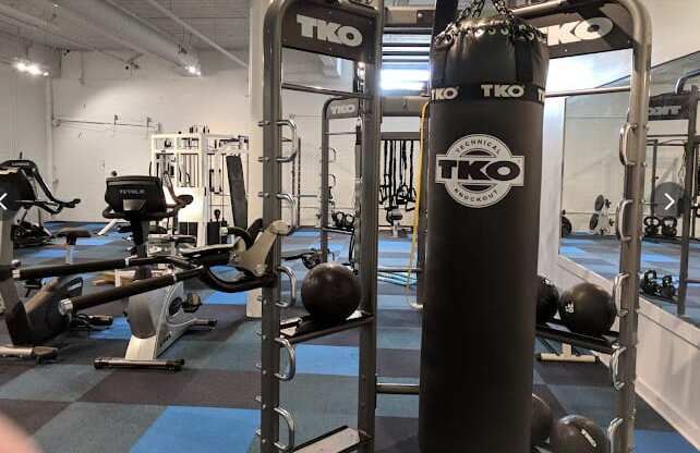 A gym with a TKO punching bag and various exercise equipment.