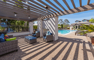 a covered patio with chairs and a pool