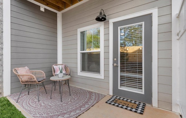 a front porch with two chairs and a table and a door