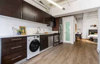 a kitchen with a washer and dryer and a living room with a door