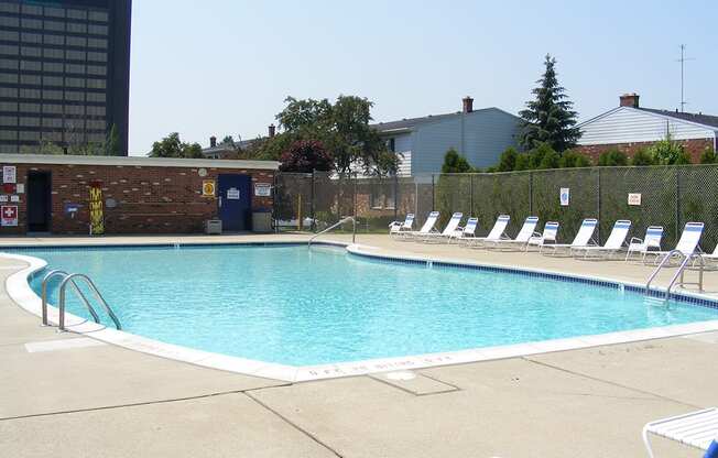 a swimming pool with chaise lounge chairs and a building in the background