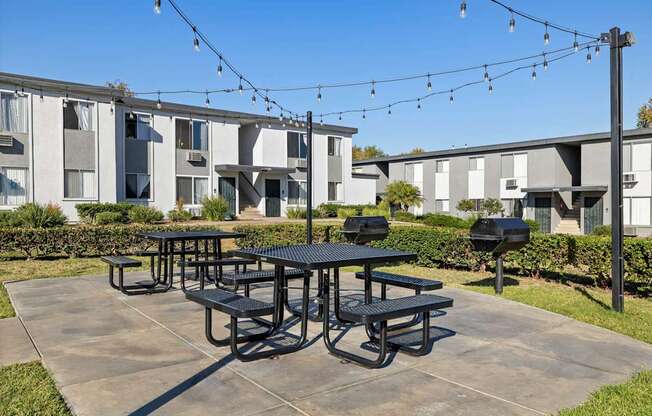 A black picnic table is in the middle of a concrete patio.