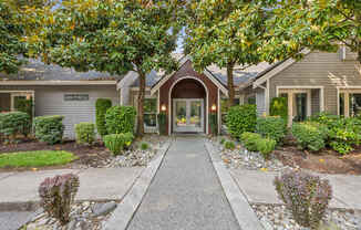 The image shows a building entrance with a pathway leading to a set of double doors.