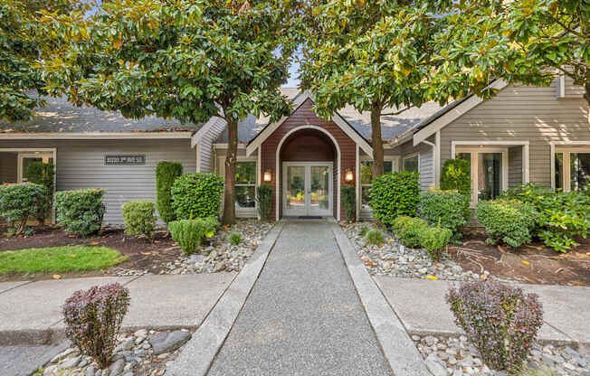 The image shows a building entrance with a pathway leading to a set of double doors.