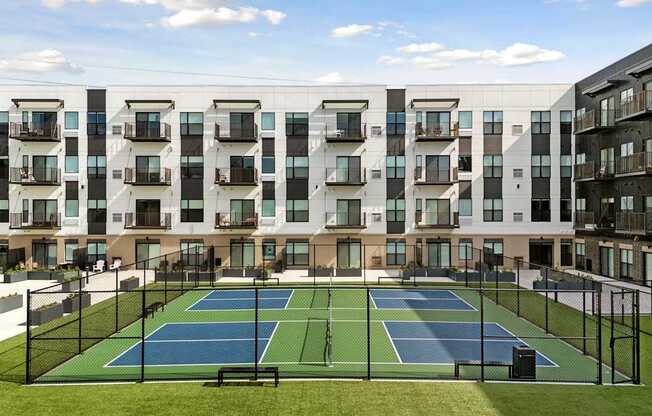A tennis court is located in the courtyard of apartment buildings.