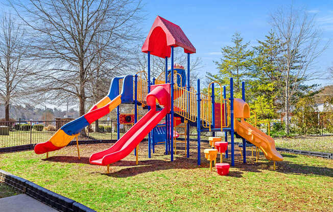 A playground with a red, yellow and blue slide.