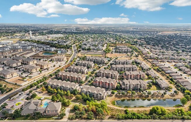 A bird's eye view of a residential area with multiple apartment buildings and a lake.
