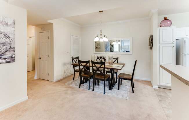 a dining room with a table and chairs and a kitchen with a refrigerator