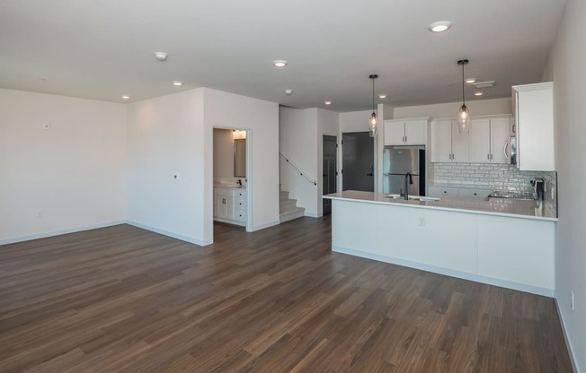 a kitchen and living room with white walls and wood flooring at The Crossings at Windsong, Arizona