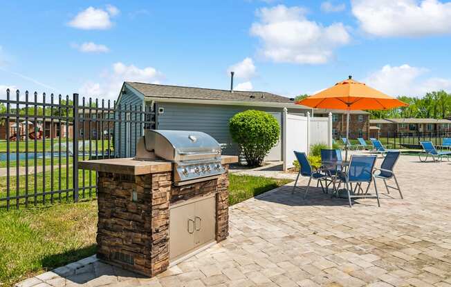 A patio with a grill and chairs is set up.