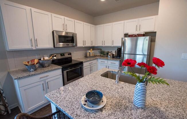 a kitchen with white cabinets and a counter with red roses