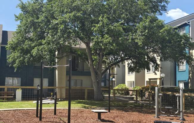 a playground with a tree in front of an apartment building