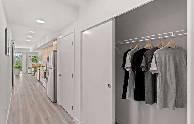 A hallway with a row of doors and clothes hanging on a rail.