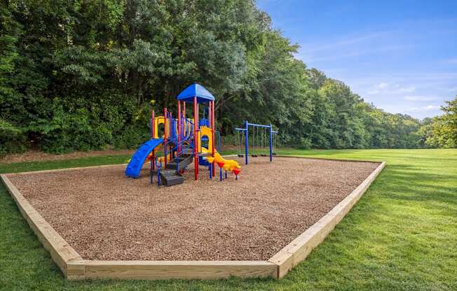 A playground with a blue and yellow slide and a red and yellow swing set.