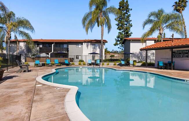 A swimming pool surrounded by palm trees and a building.