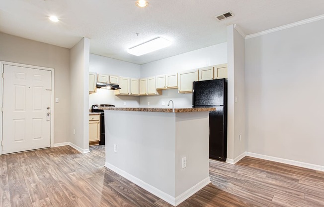 a kitchen with an island and a black refrigerator