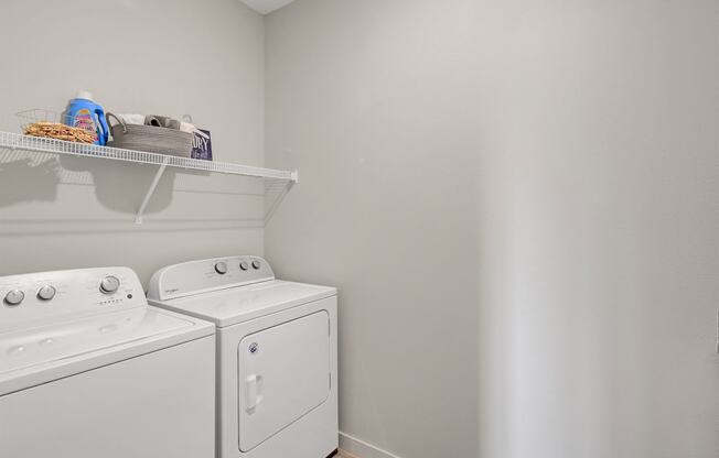 a white washer and dryer in a laundry room with a shelf above it