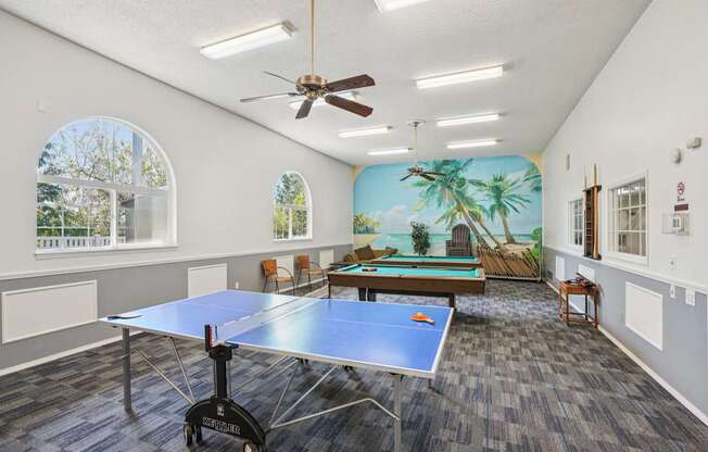 A room with a ping pong table and a mural on the wall.