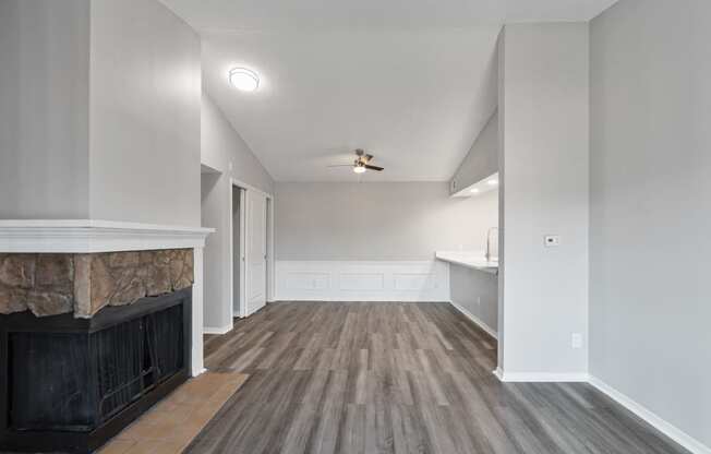 an empty living room with a fireplace and a kitchen