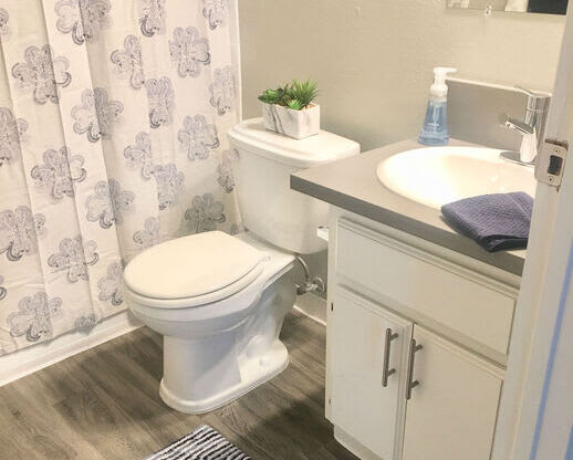 a bathroom with a toilet and a sink and a shower curtain  at The Marq Apartments LLC, Los Angeles
